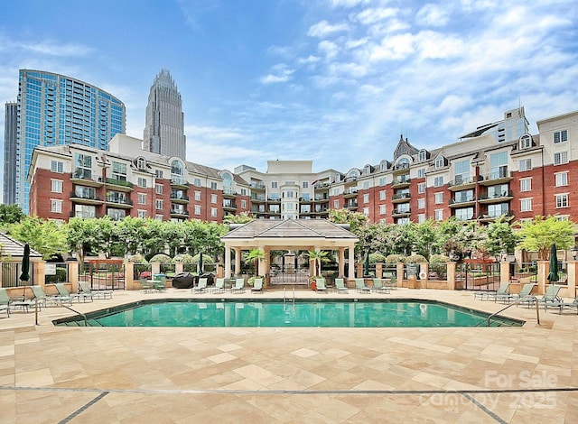 pool with a gazebo, a patio area, fence, and a city view