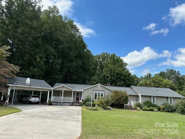 ranch-style home with covered porch, a front yard, and a carport