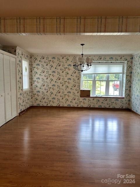 empty room featuring wood-type flooring and an inviting chandelier