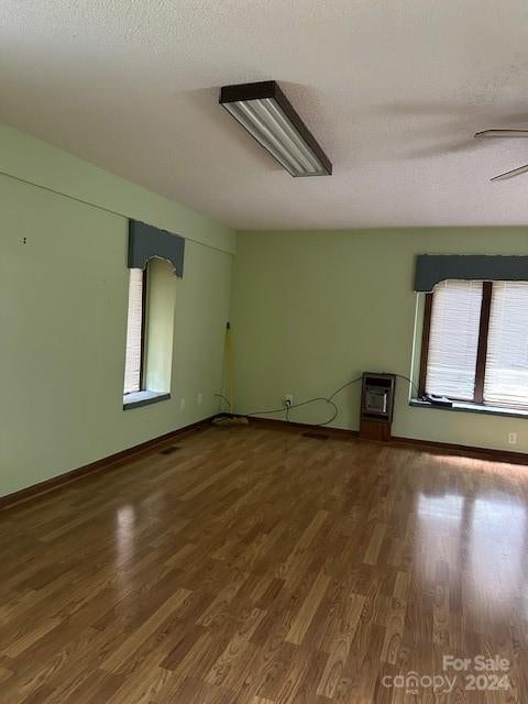 interior space with ceiling fan, dark hardwood / wood-style flooring, heating unit, and a textured ceiling