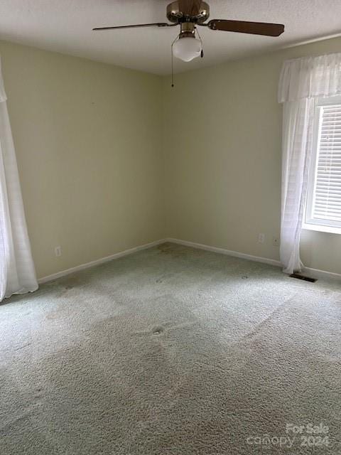 carpeted spare room with ceiling fan