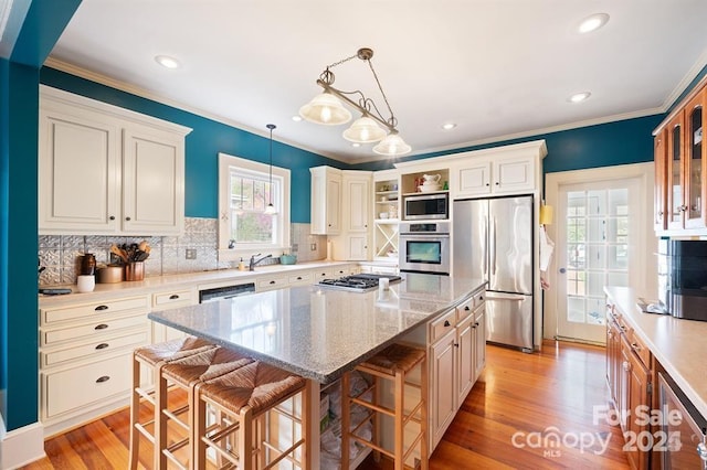 kitchen featuring stainless steel appliances, decorative light fixtures, a center island, a kitchen bar, and light stone countertops