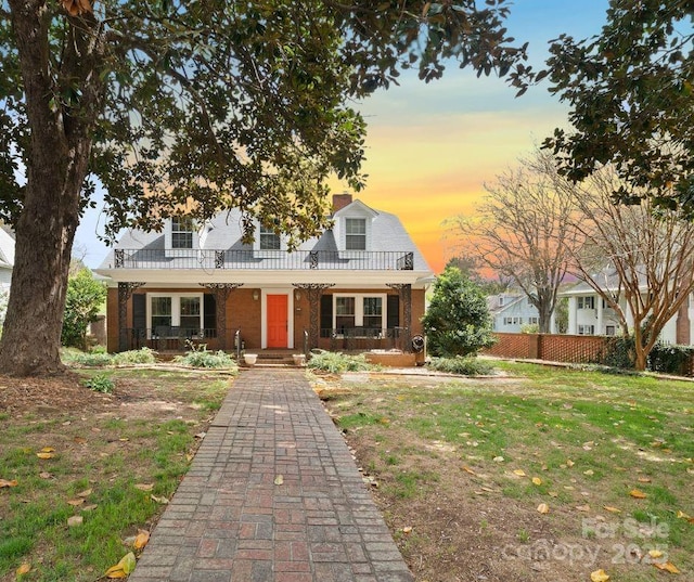 cape cod-style house featuring a yard and a porch