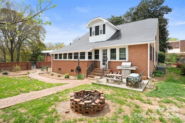 rear view of property with a patio, central AC, a fire pit, and a yard