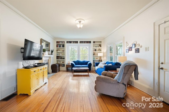 living room with ornamental molding, built in features, and light hardwood / wood-style flooring