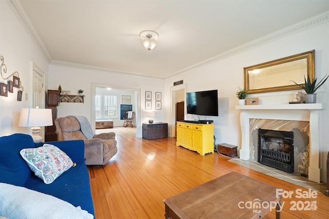 living room with ornamental molding, a premium fireplace, and hardwood / wood-style floors