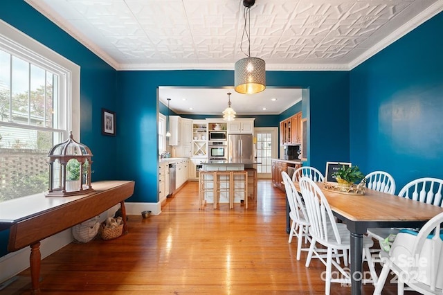 dining room with ornamental molding and light hardwood / wood-style floors