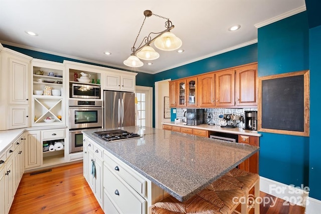 kitchen with a kitchen breakfast bar, light hardwood / wood-style floors, stainless steel appliances, a center island, and pendant lighting