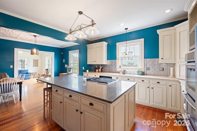 kitchen featuring a kitchen island, crown molding, pendant lighting, and hardwood / wood-style floors