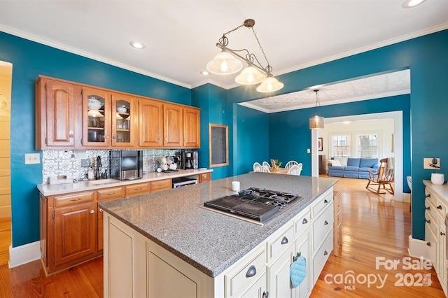 kitchen featuring stainless steel gas cooktop, tasteful backsplash, light hardwood / wood-style floors, hanging light fixtures, and a kitchen island