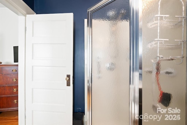 bathroom with hardwood / wood-style flooring and an enclosed shower