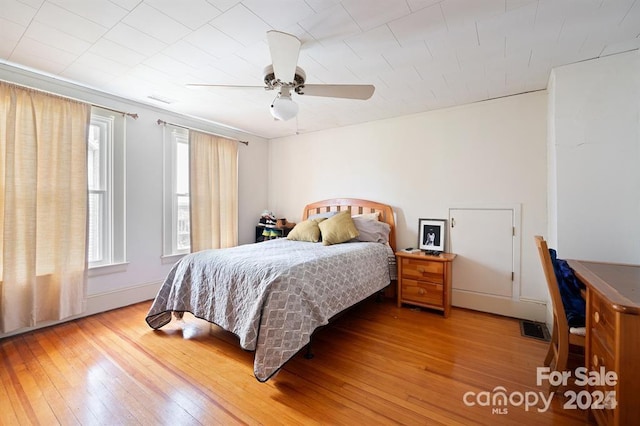 bedroom featuring multiple windows, ceiling fan, and light wood-type flooring