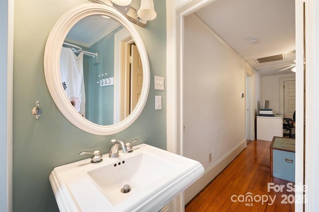 bathroom featuring hardwood / wood-style flooring, ceiling fan, ornamental molding, and sink