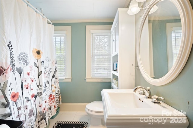 bathroom featuring toilet, tile patterned flooring, crown molding, and plenty of natural light