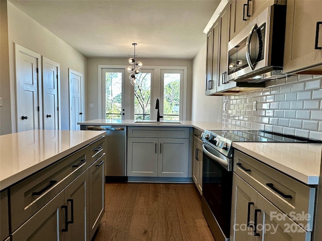 kitchen with dark wood-type flooring, gray cabinetry, sink, pendant lighting, and appliances with stainless steel finishes