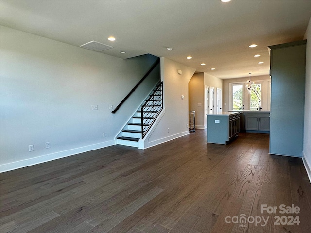 unfurnished living room with sink, a chandelier, and dark hardwood / wood-style floors