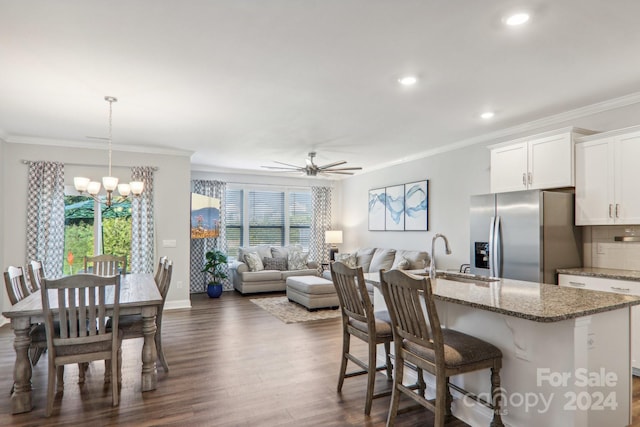 kitchen with ceiling fan with notable chandelier, stainless steel fridge, sink, white cabinetry, and plenty of natural light