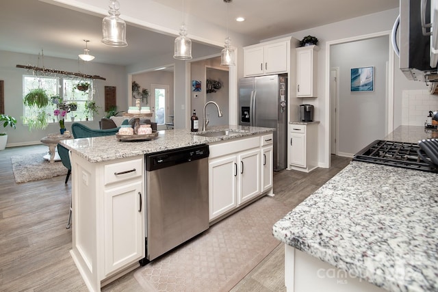 kitchen featuring a center island with sink, appliances with stainless steel finishes, sink, a wealth of natural light, and white cabinets