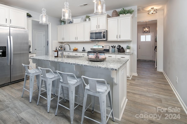 kitchen with pendant lighting, white cabinetry, an island with sink, sink, and appliances with stainless steel finishes