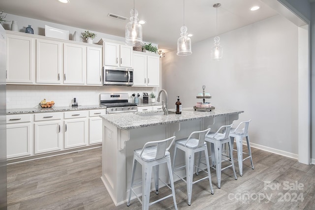 kitchen with a kitchen island with sink, appliances with stainless steel finishes, white cabinetry, and sink