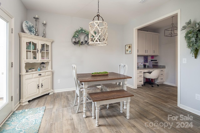 dining room with built in desk, a notable chandelier, and wood-type flooring