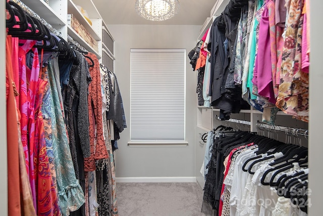 walk in closet with carpet and an inviting chandelier