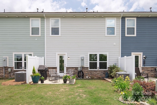 rear view of property featuring central AC unit, a lawn, and a patio