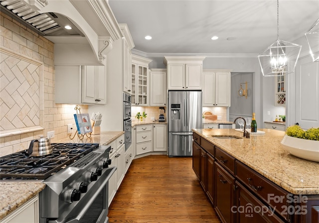 kitchen with dark brown cabinetry, sink, light stone counters, decorative light fixtures, and stainless steel appliances