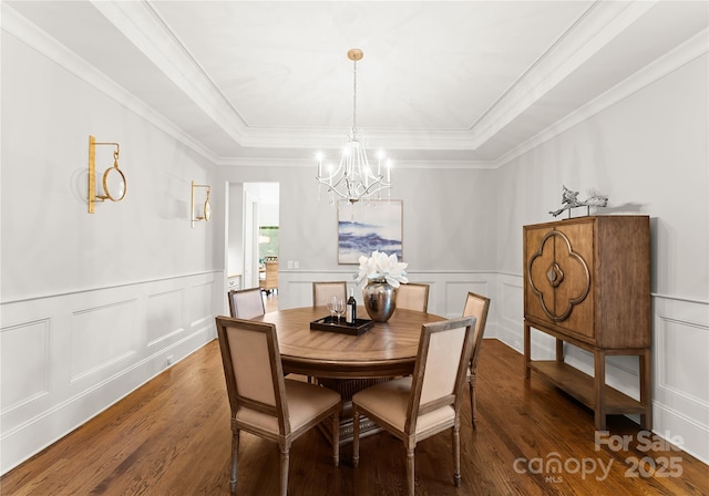 dining area featuring a notable chandelier, a tray ceiling, ornamental molding, and dark hardwood / wood-style floors