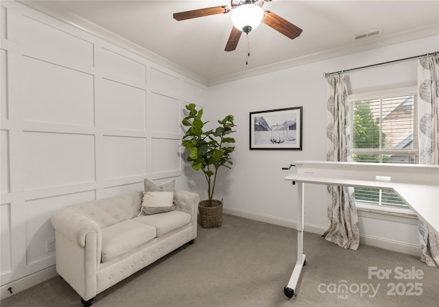 sitting room with ceiling fan, ornamental molding, and light carpet