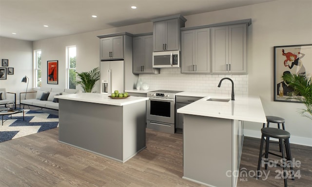 kitchen featuring gray cabinets, a center island, sink, appliances with stainless steel finishes, and hardwood / wood-style flooring