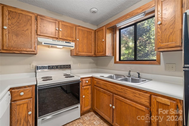 kitchen featuring a textured ceiling, sink, white appliances, and light tile patterned flooring