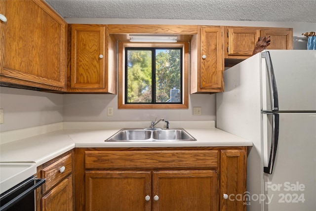 kitchen with a textured ceiling, sink, and stainless steel fridge