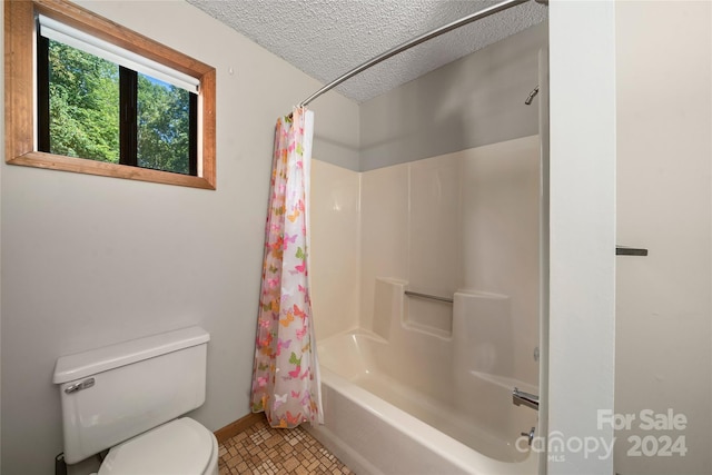 bathroom featuring a textured ceiling, shower / bath combo with shower curtain, and toilet