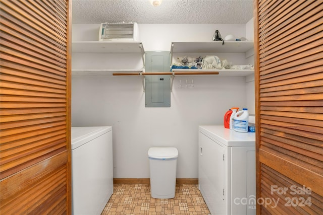 laundry area featuring electric panel, washing machine and clothes dryer, and a textured ceiling