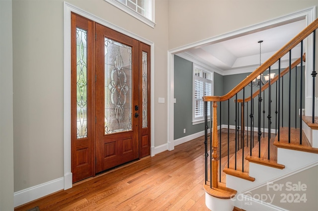 foyer with light hardwood / wood-style floors, crown molding, and a chandelier