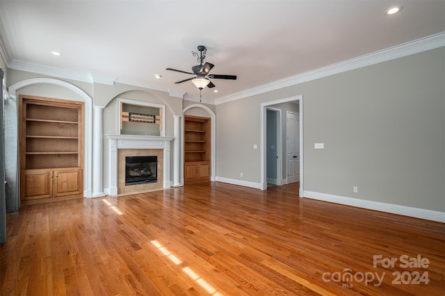 unfurnished living room featuring ceiling fan, ornamental molding, a tile fireplace, and hardwood / wood-style floors