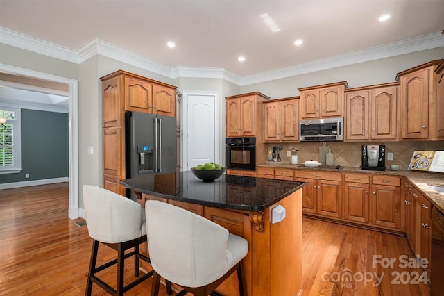 kitchen featuring ornamental molding, a center island, light hardwood / wood-style flooring, and stainless steel appliances