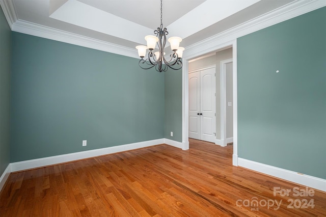 unfurnished room with crown molding, a notable chandelier, and hardwood / wood-style floors