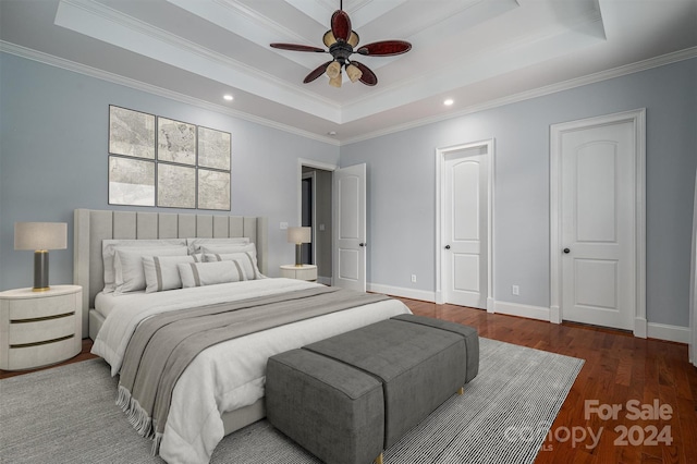 bedroom featuring ornamental molding, dark wood-type flooring, a tray ceiling, and ceiling fan