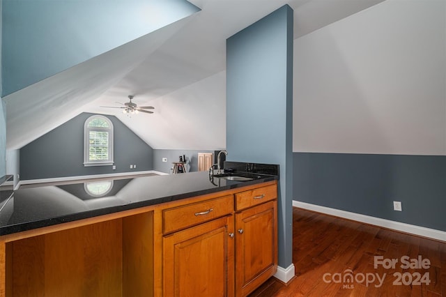 kitchen with kitchen peninsula, sink, dark wood-type flooring, and vaulted ceiling