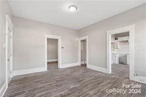 unfurnished bedroom with a walk in closet, connected bathroom, dark hardwood / wood-style floors, and a closet