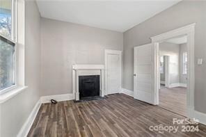 unfurnished living room featuring a healthy amount of sunlight and dark hardwood / wood-style flooring