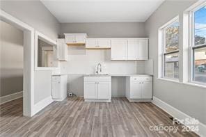 kitchen featuring light hardwood / wood-style floors, white cabinetry, and sink