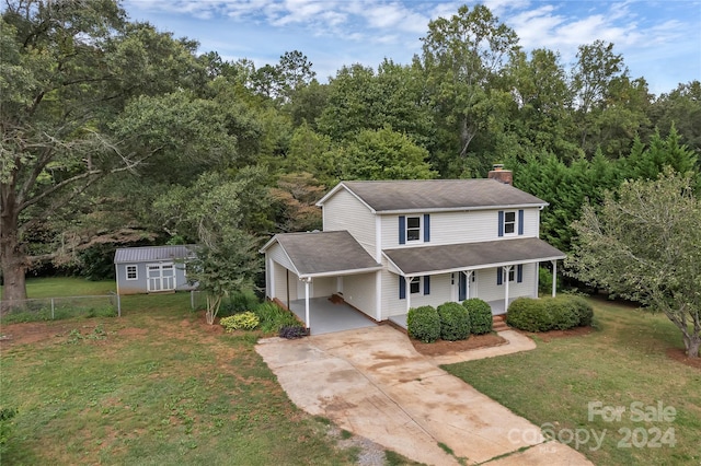 front of property featuring a garage, a storage unit, a front lawn, and covered porch