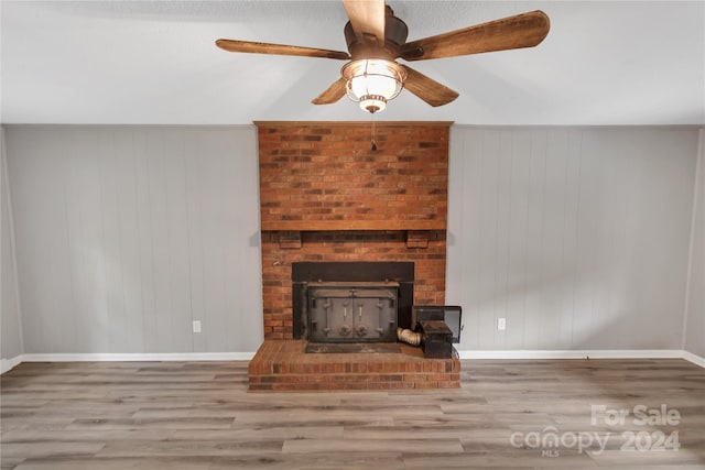 unfurnished living room with hardwood / wood-style floors, ceiling fan, and a brick fireplace