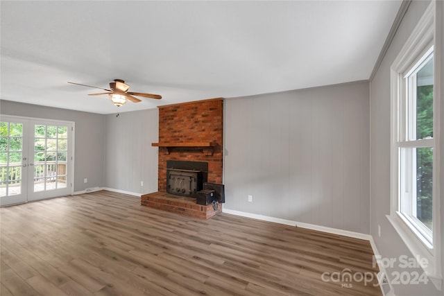 unfurnished living room featuring ceiling fan, a fireplace, crown molding, and wood-type flooring