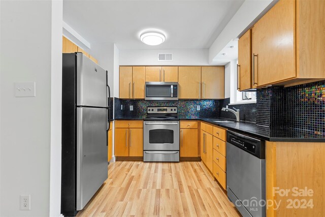 kitchen with backsplash, stainless steel appliances, light hardwood / wood-style floors, and sink