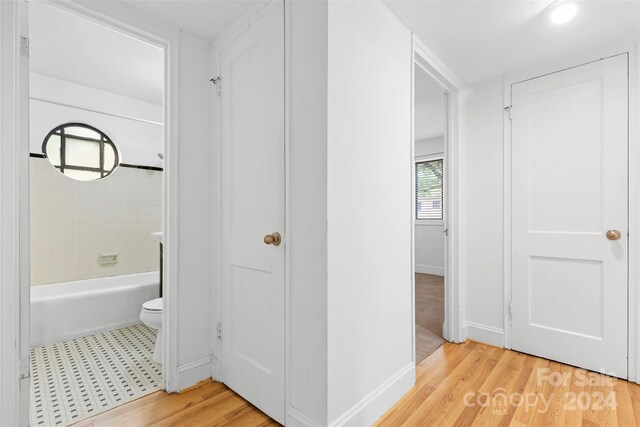 bathroom featuring wood-type flooring, toilet, and tiled shower / bath combo