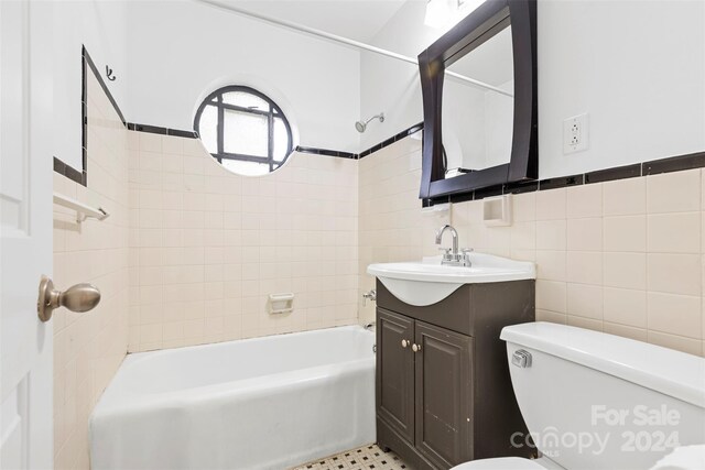 full bathroom with vanity, toilet, tile walls, and tiled shower / bath